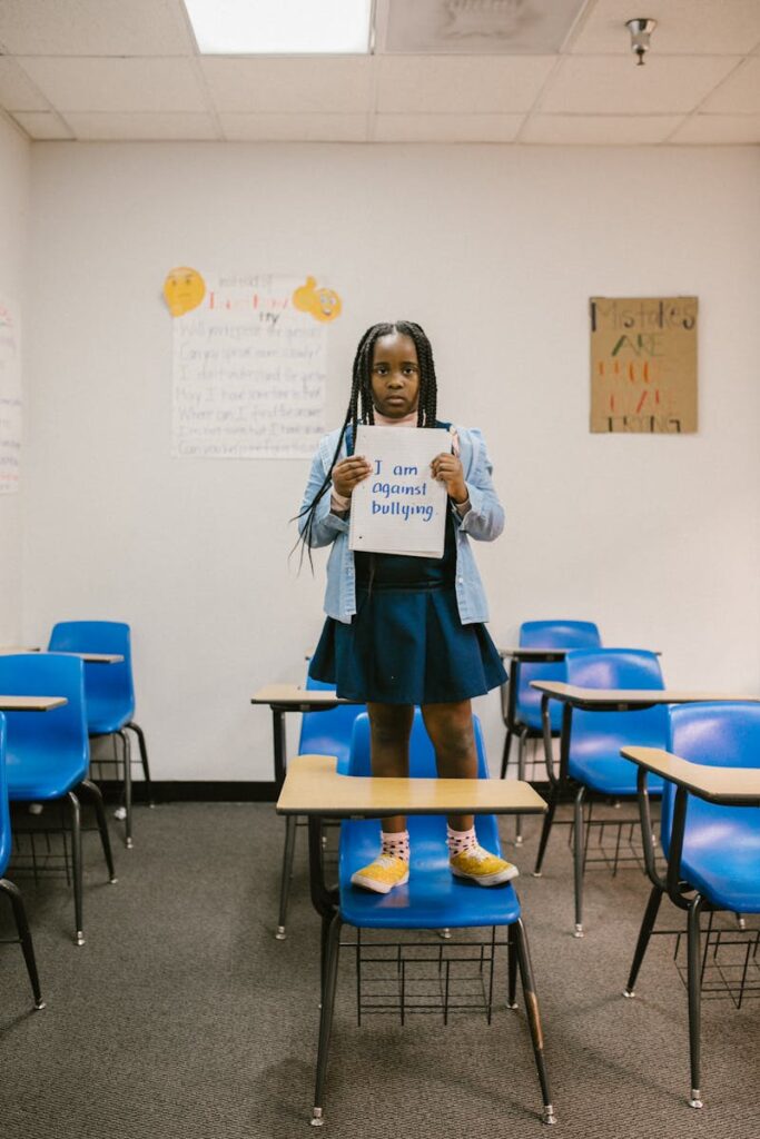 A child holds an anti-bullying sign in a classroom, promoting awareness.