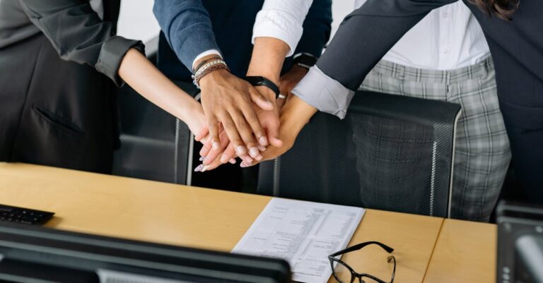 A close-up of a diverse business team stacking hands in unity, showcasing teamwork in an office setting.