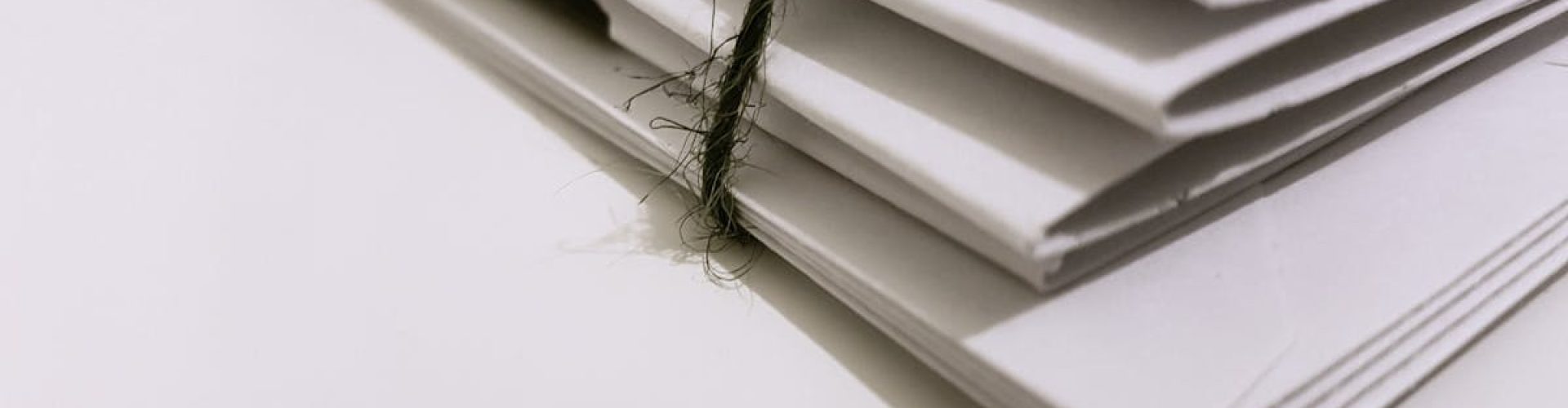 pexels-photo-1764956-1764956 Pile of white envelopes tied with a green string, showcasing a minimalist design.