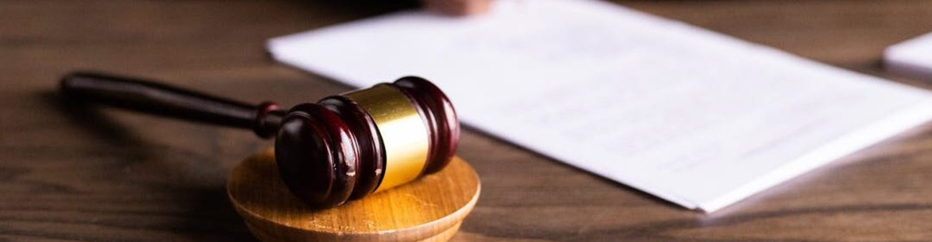 pexels-photo-6077447-6077447 Judge signing documents at desk with focus on gavel, representing law and justice.